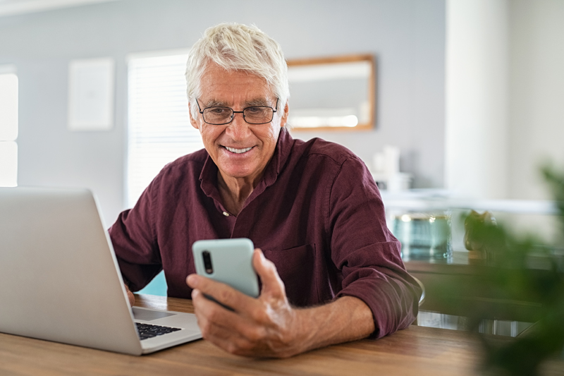 Senior Man looking at smartphone and laptop